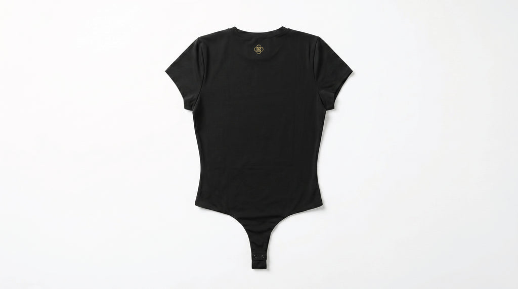Back side of a black colored bodysuit on a white background. The Five Realms logo is in gold near the neck collar. Thong bottom with snap closure.
