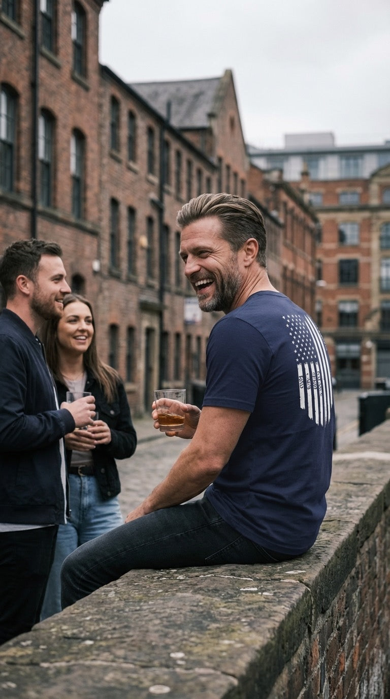 Three people sitting on a wall with brick buildings in the background