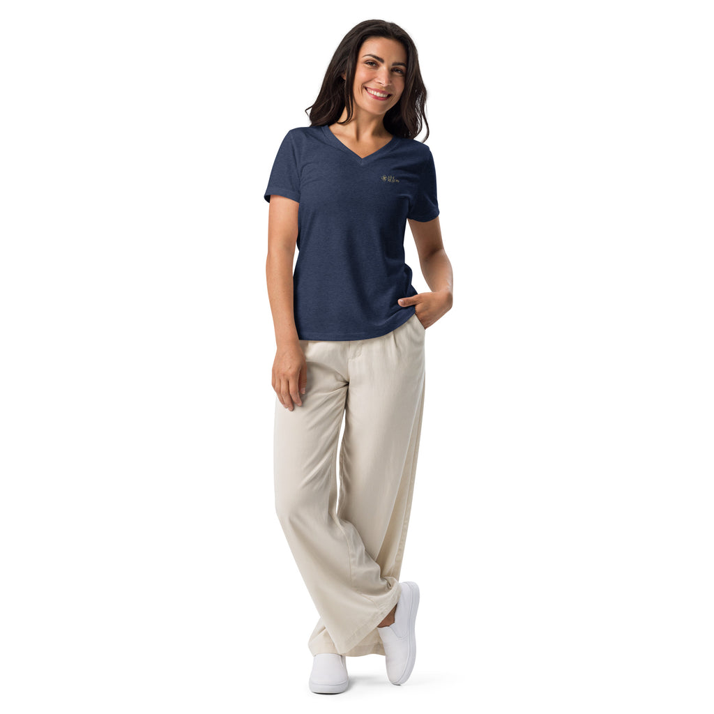 Woman wearing a navy blue t-shirt with a logo and beige pants on a white background