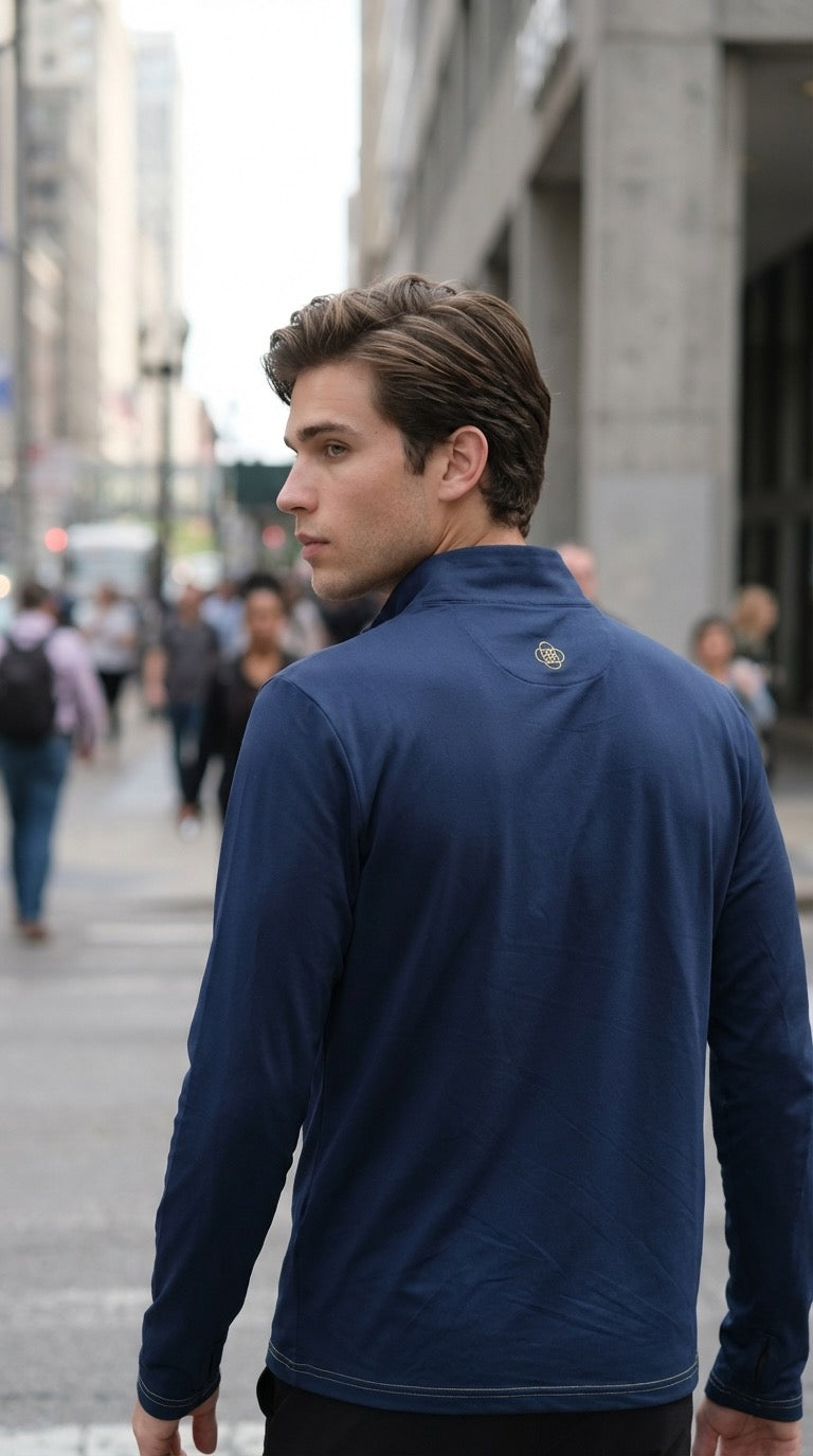 Man wearing a blue jacket with a logo on the back, standing in an urban setting.