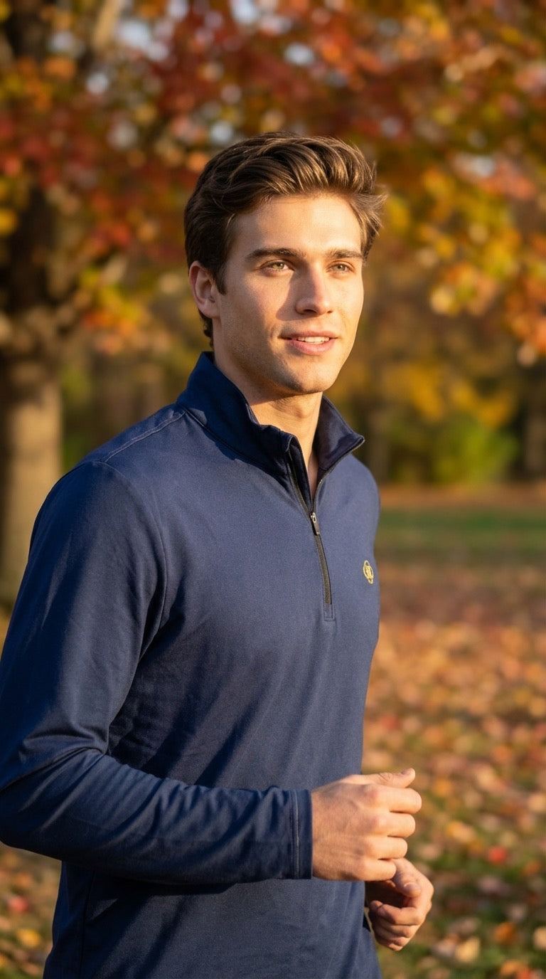 Man wearing a navy blue pullover in an outdoor setting with trees and leaves.