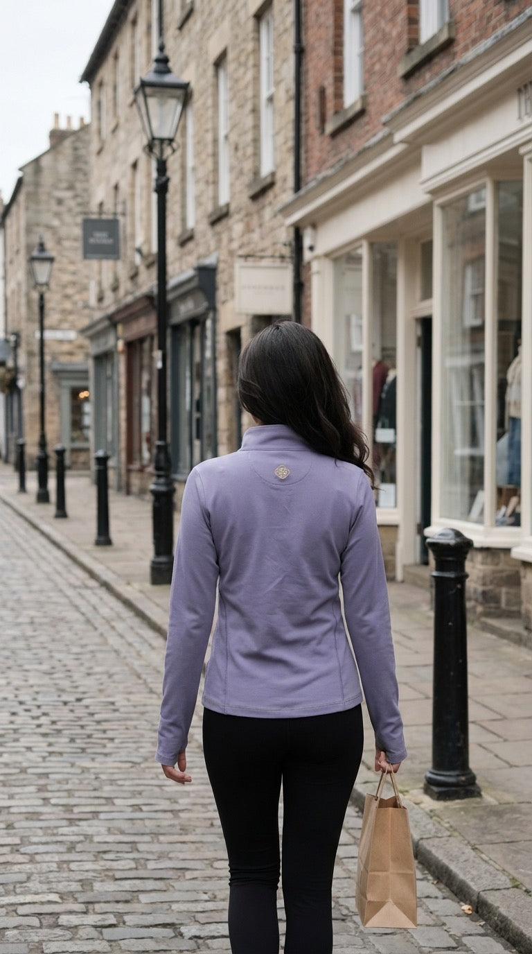 Woman walking down a street in an urban setting wearing a purple jacket.