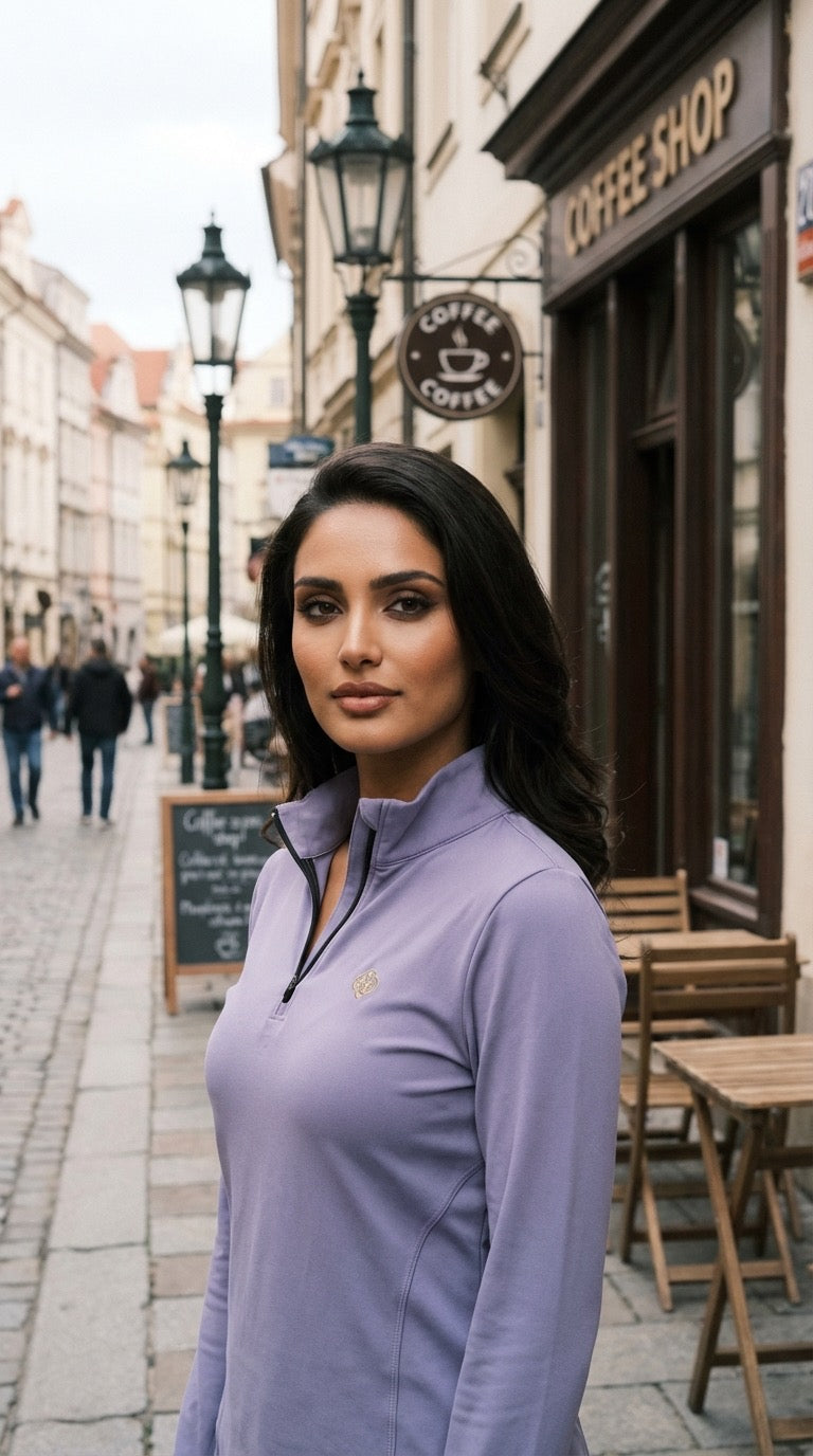 Woman in a purple jacket standing on a street with a coffee shop in the background